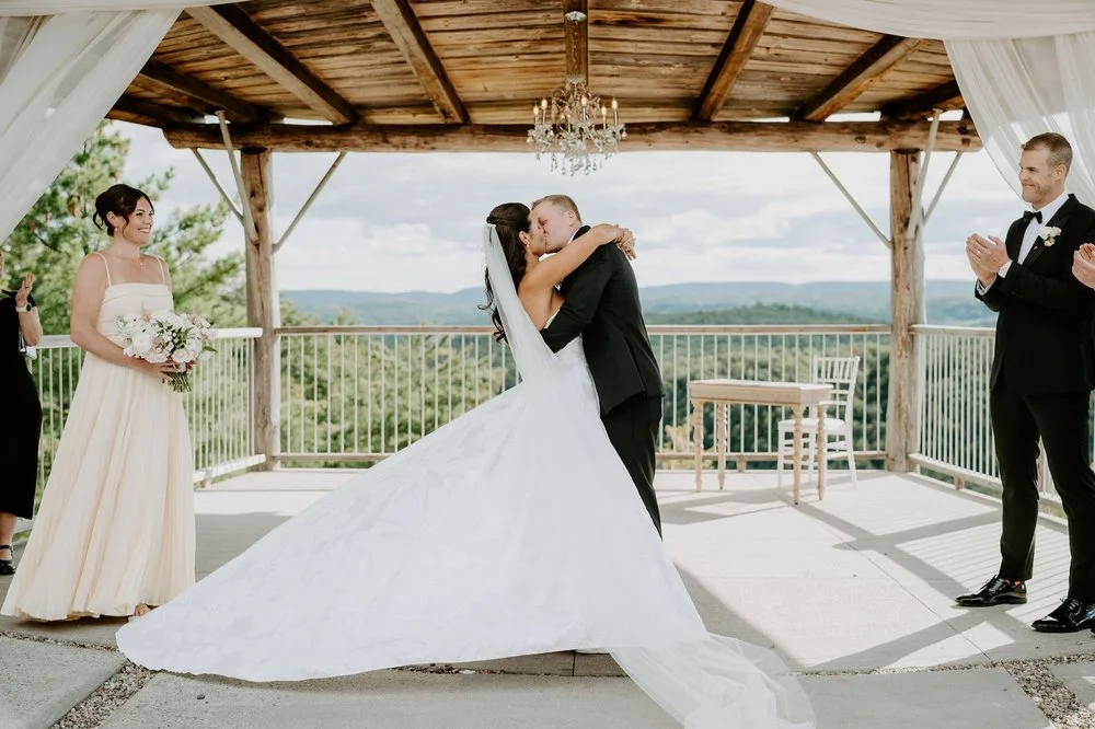Kylie and Will's first kiss under the draped pavilion at Le Belvedere, the Gatineau Hills behind them