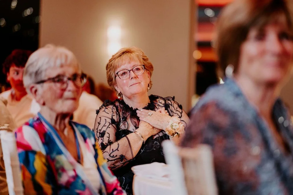 A guest in black lace holding her hands to her heart during the speeches