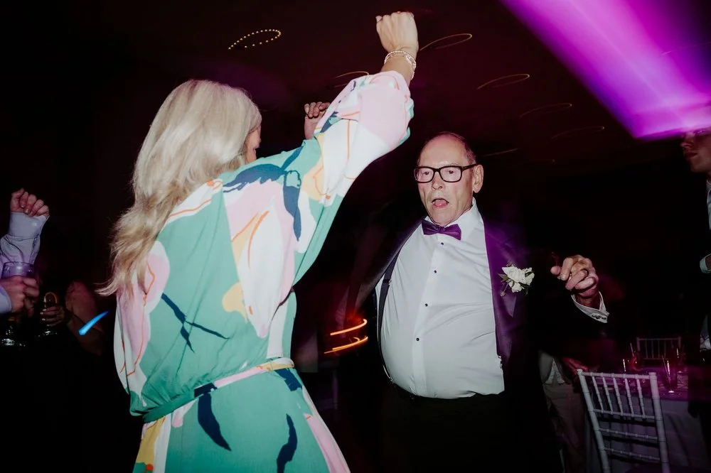 A man in a purple bow tie dancing with a woman in a colourful dress