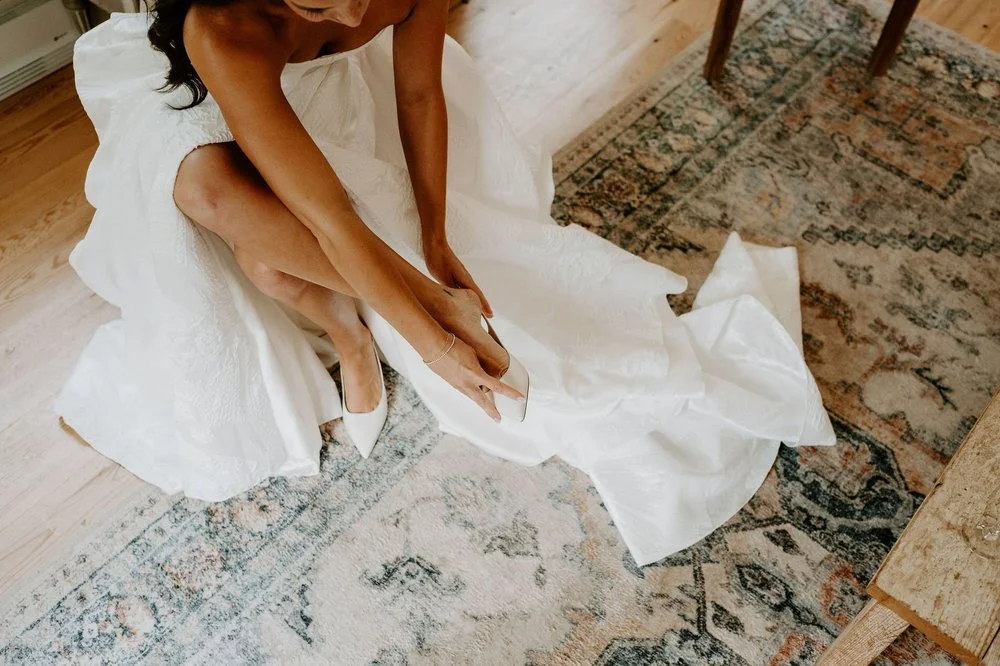 Kylie slipping on white pointed heels, her gown spread across a vintage rug