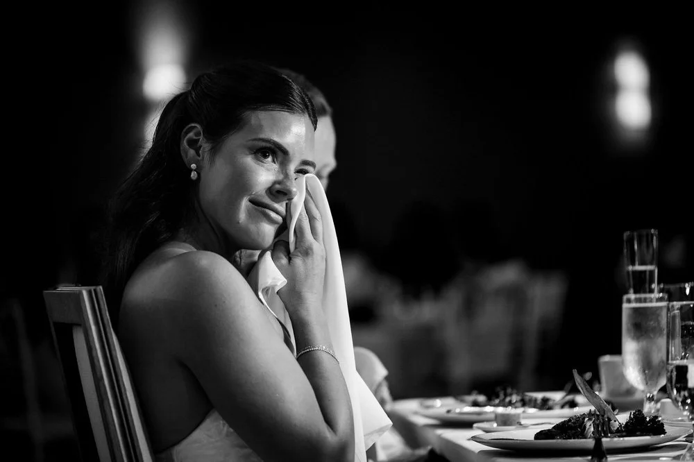 Black and white photo of Kylie wiping away a tear with a napkin during the speeches