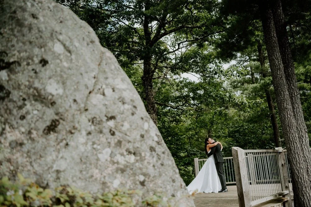 Kylie and Will embracing on the lookout deck at Le Belvedere, framed by a large granite boulder