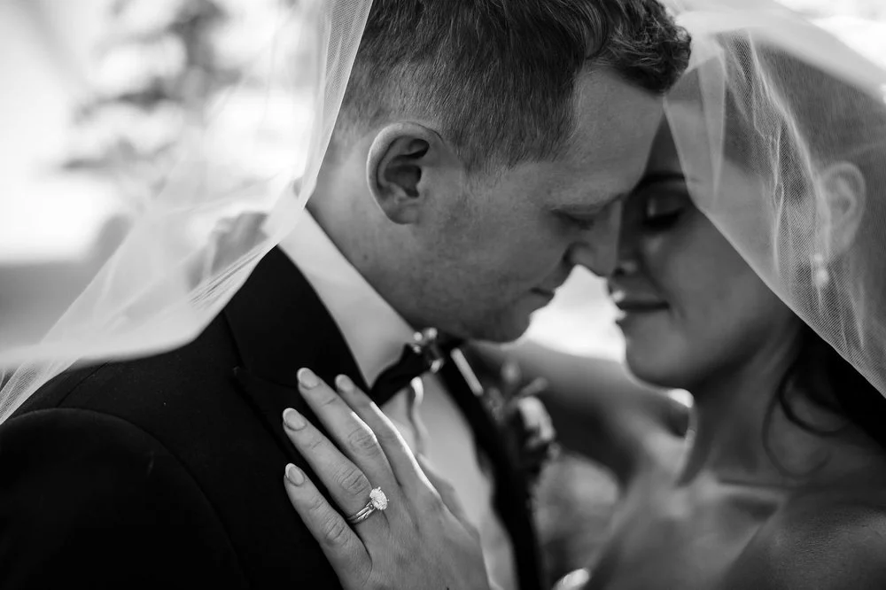 Black and white close-up of Kylie and Will under her veil, her engagement ring resting on his lapel