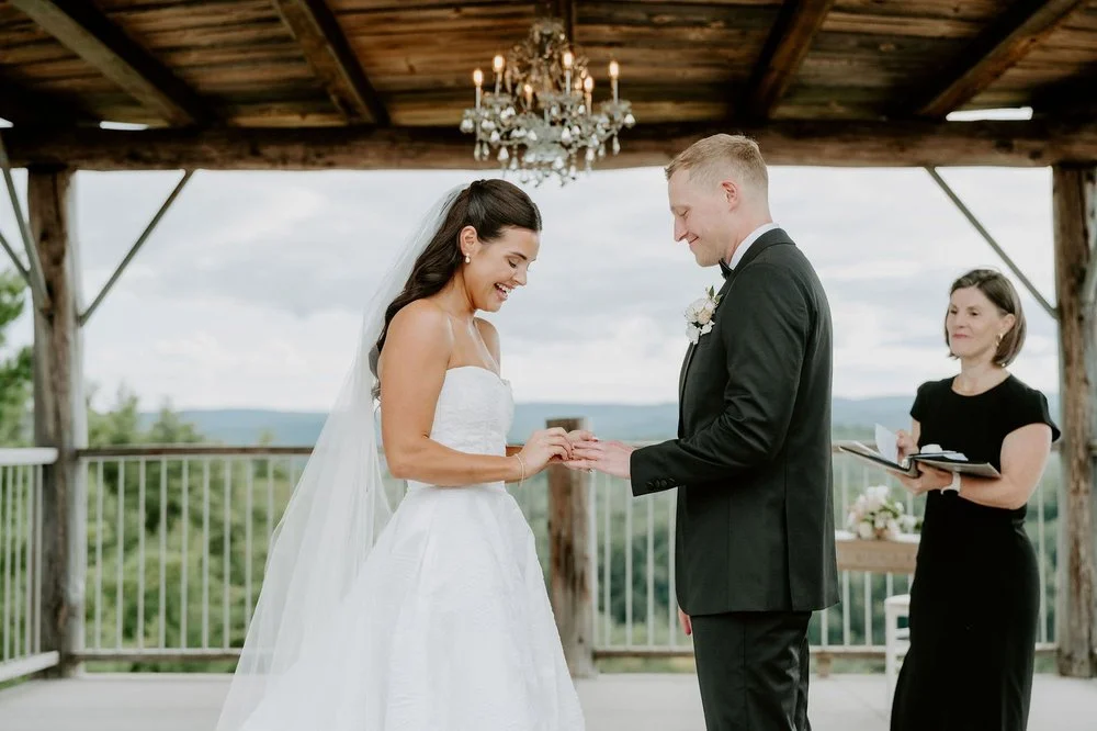 Kylie laughing as Will slides on her wedding ring under the chandelier at Le Belvedere