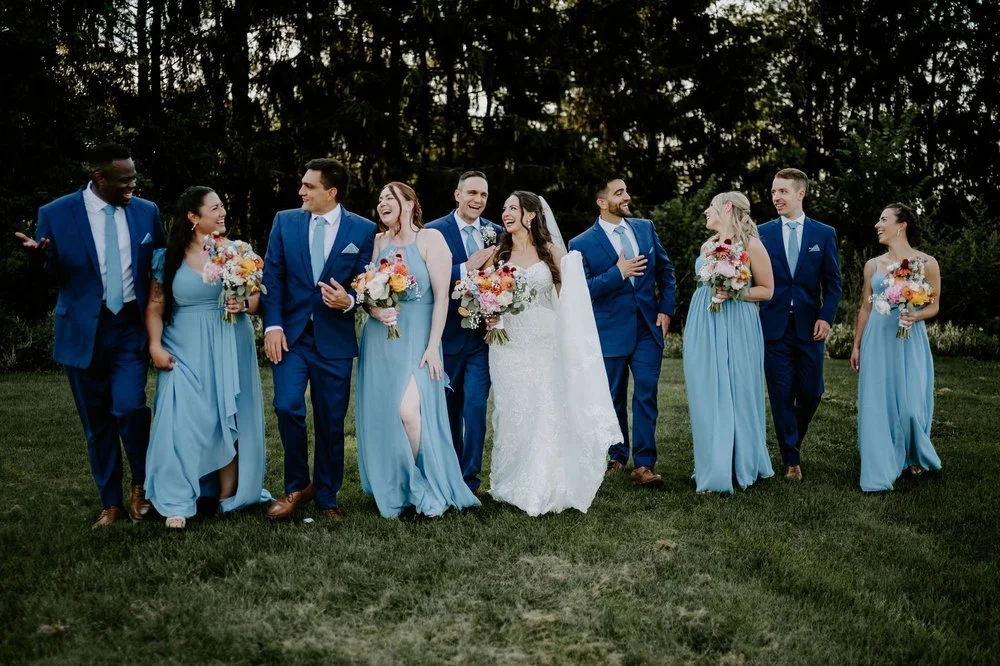 Holly and Petar's wedding party walking across the lawn at Evermore, groomsmen in blue and bridesmaids in dusty blue