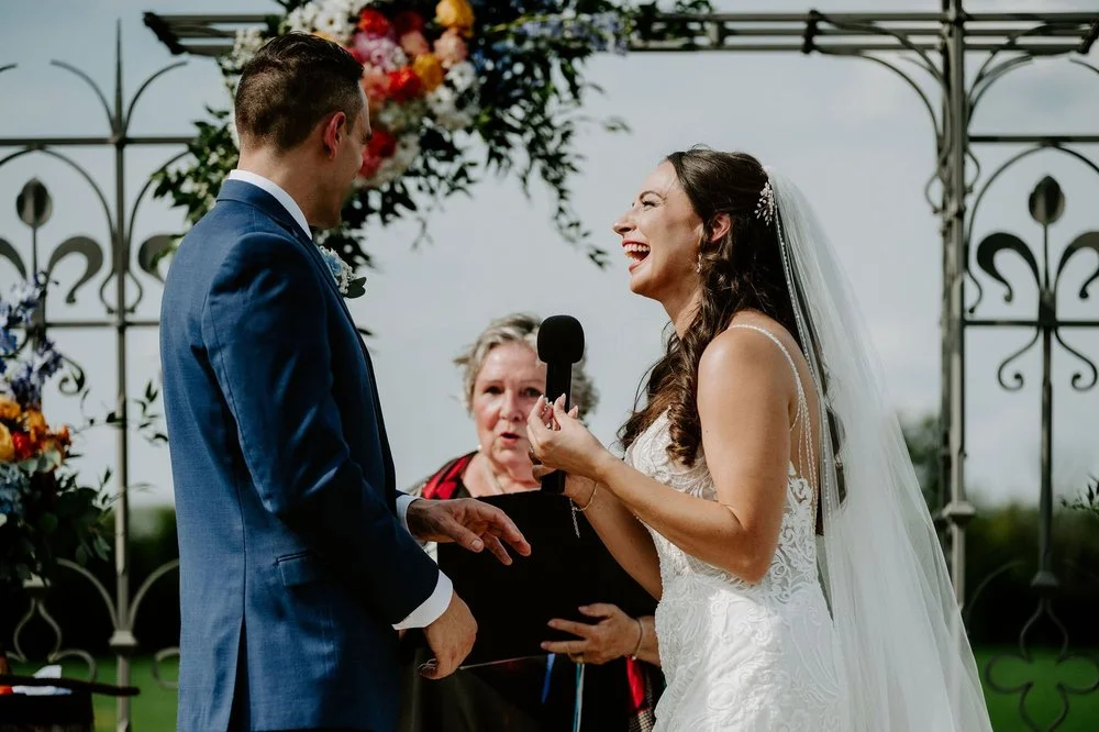 Holly laughing as she reads her vows into a microphone at Evermore