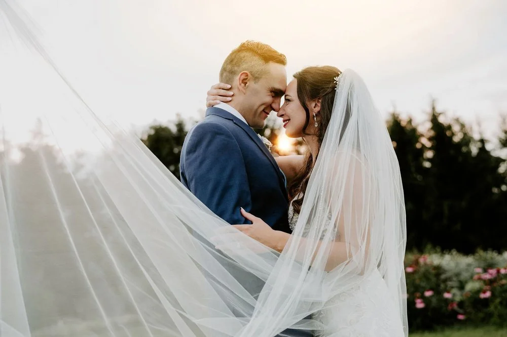 Holly and Petar embracing nose to nose at sunset, her veil sweeping across the frame