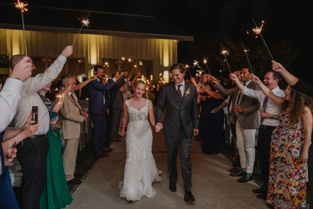 bride and groom walking down the aisle with sparklers towards their first dance location