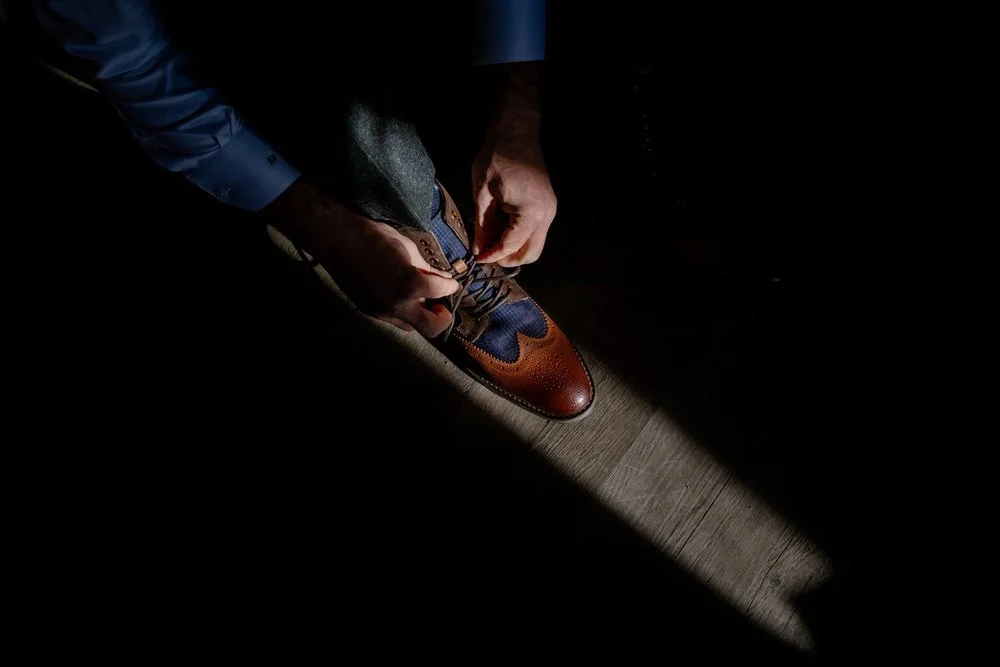 dramatic photo of a groom putting on his shoes