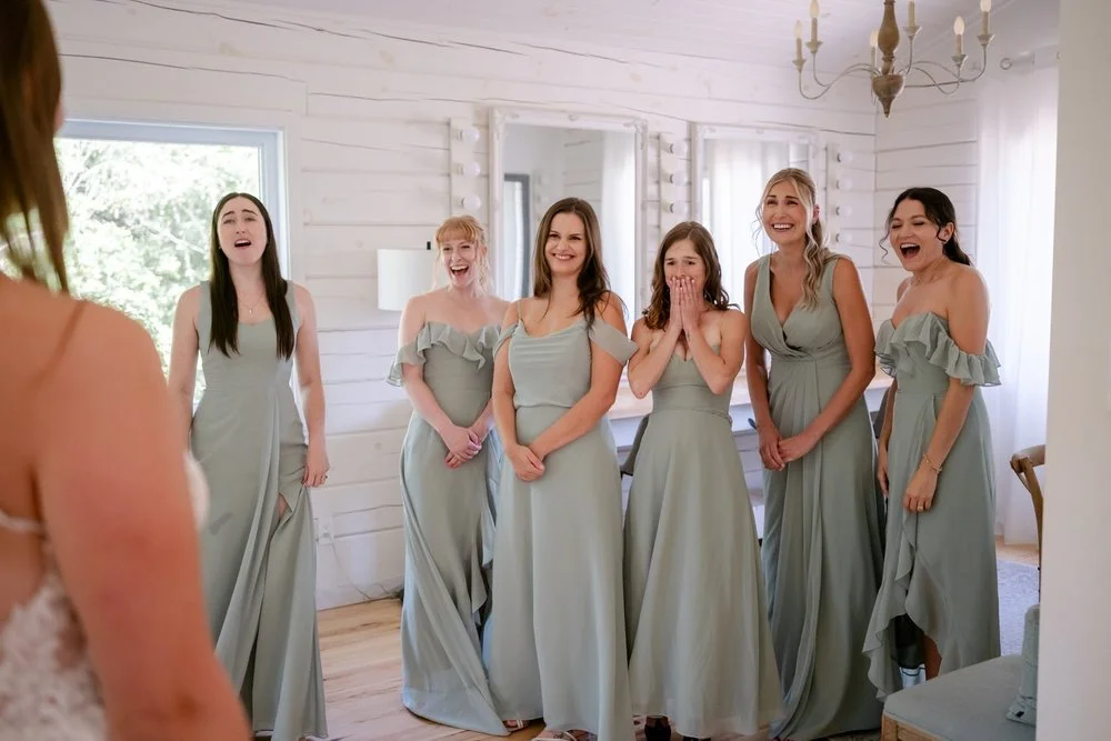 photograph of a bride revealing her dress to her bridesmaids at le belvedere