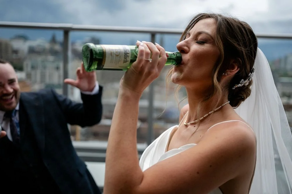 a photo of a bride drinking liquor straight from the bottle