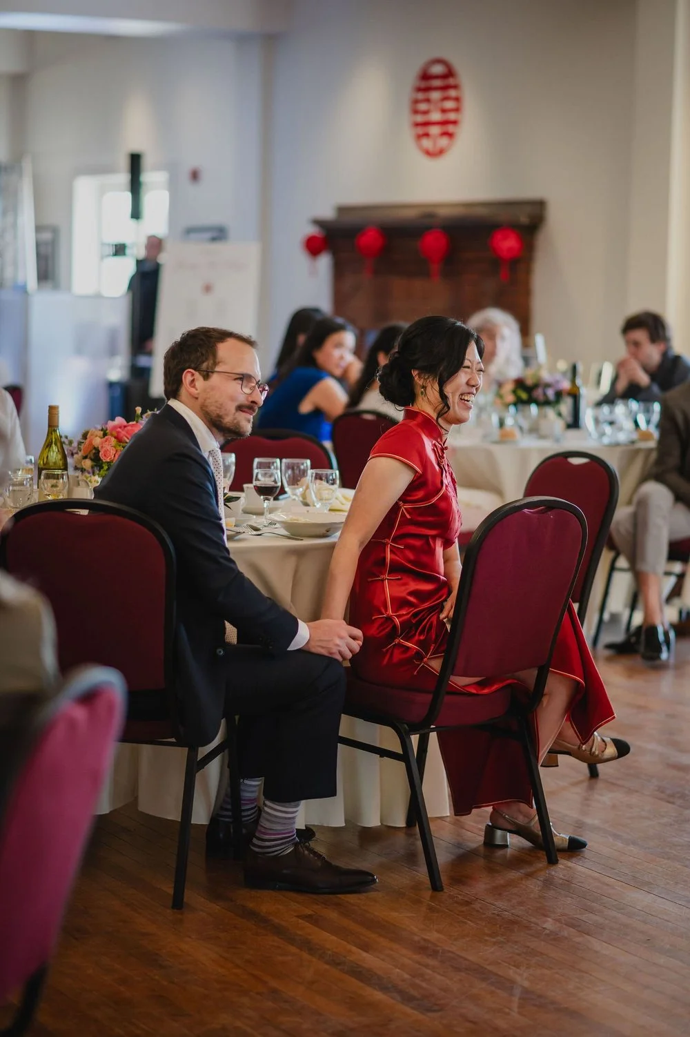 a bride and groom laughing at a wedding speech