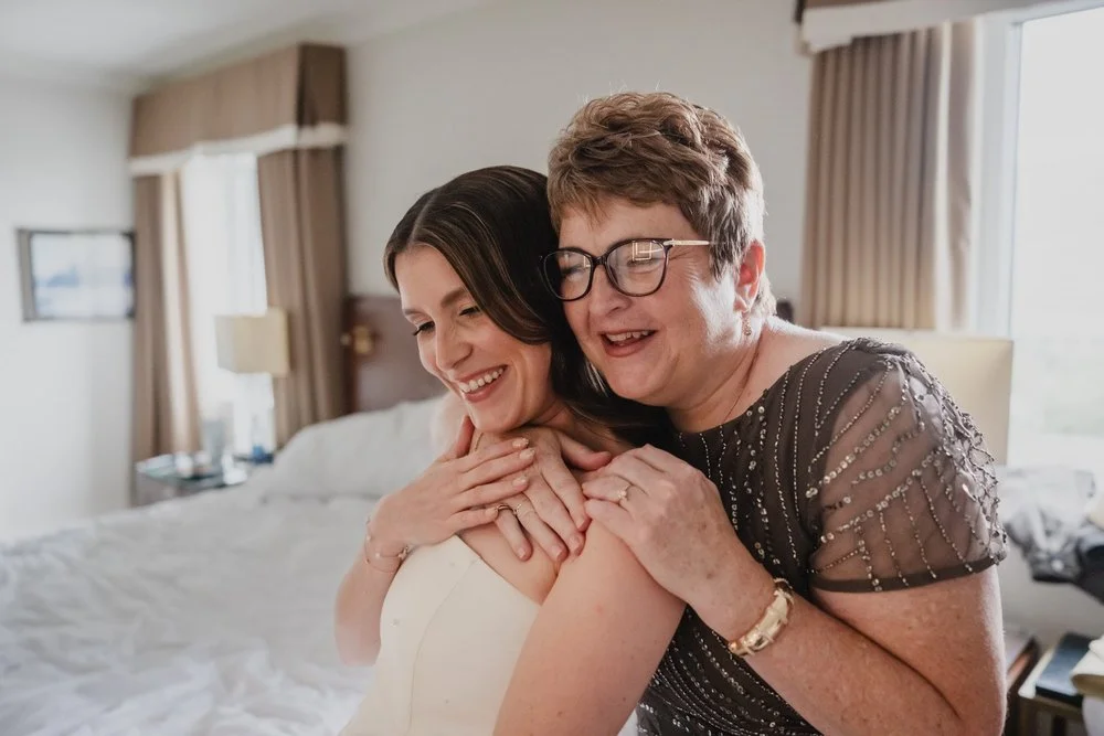 a photo of a mother and her daughter hugging right after she gets into her wedding dress