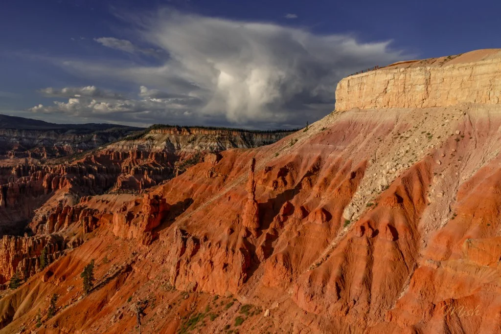 Scenic view of layered red rock formations under a cloudy sky, showcasing the natural beauty of a canyon landscape.