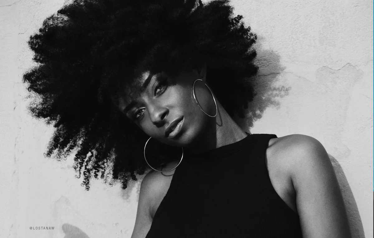 Black and white portrait of a woman with a natural afro and large hoop earrings